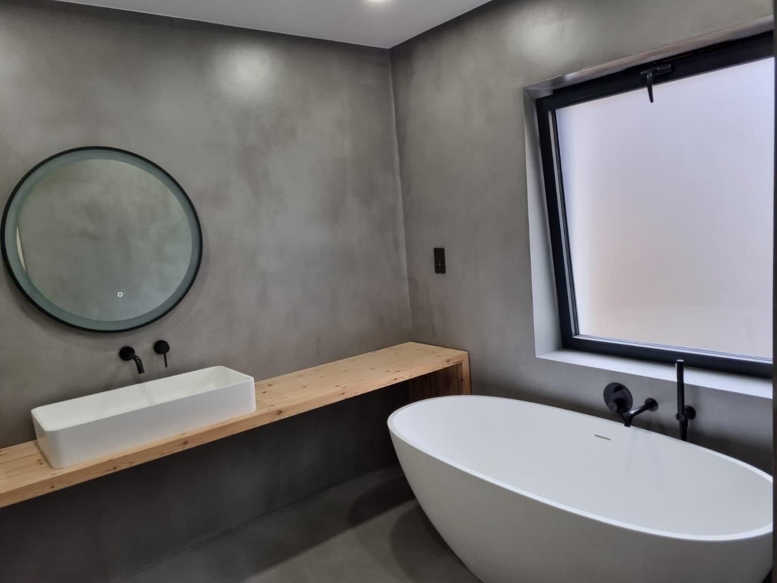 Microcement bathroom with freestanding bath and timber vanity