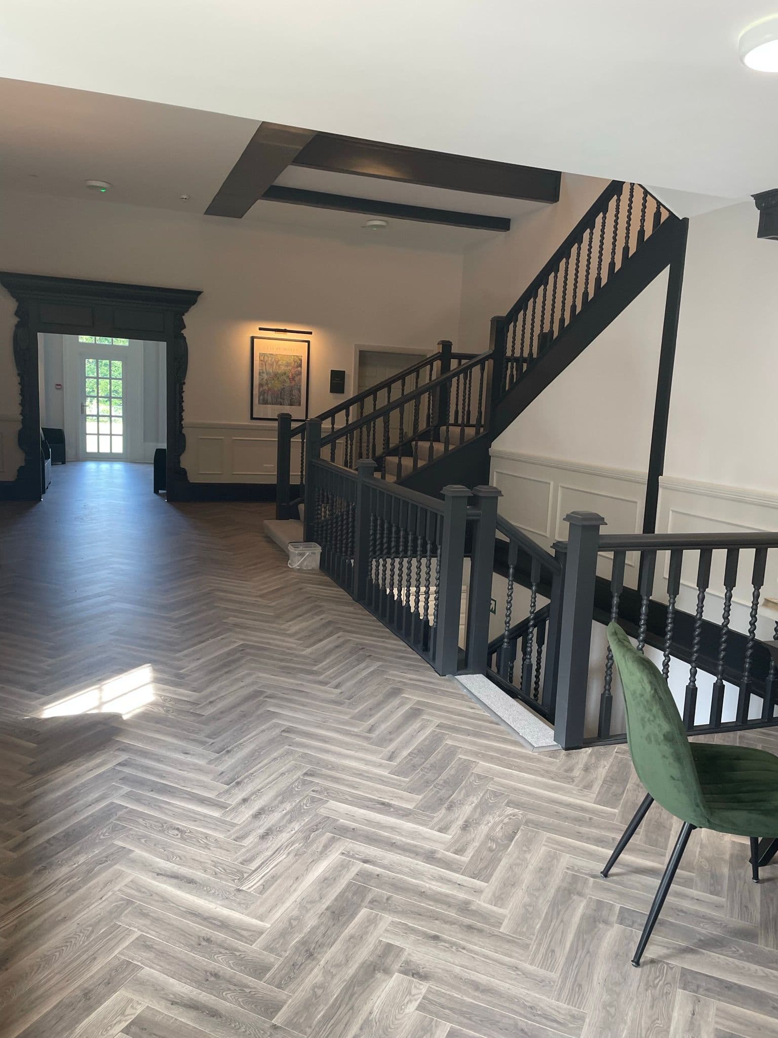 Residents' hall with herringbone floor and painted staircase