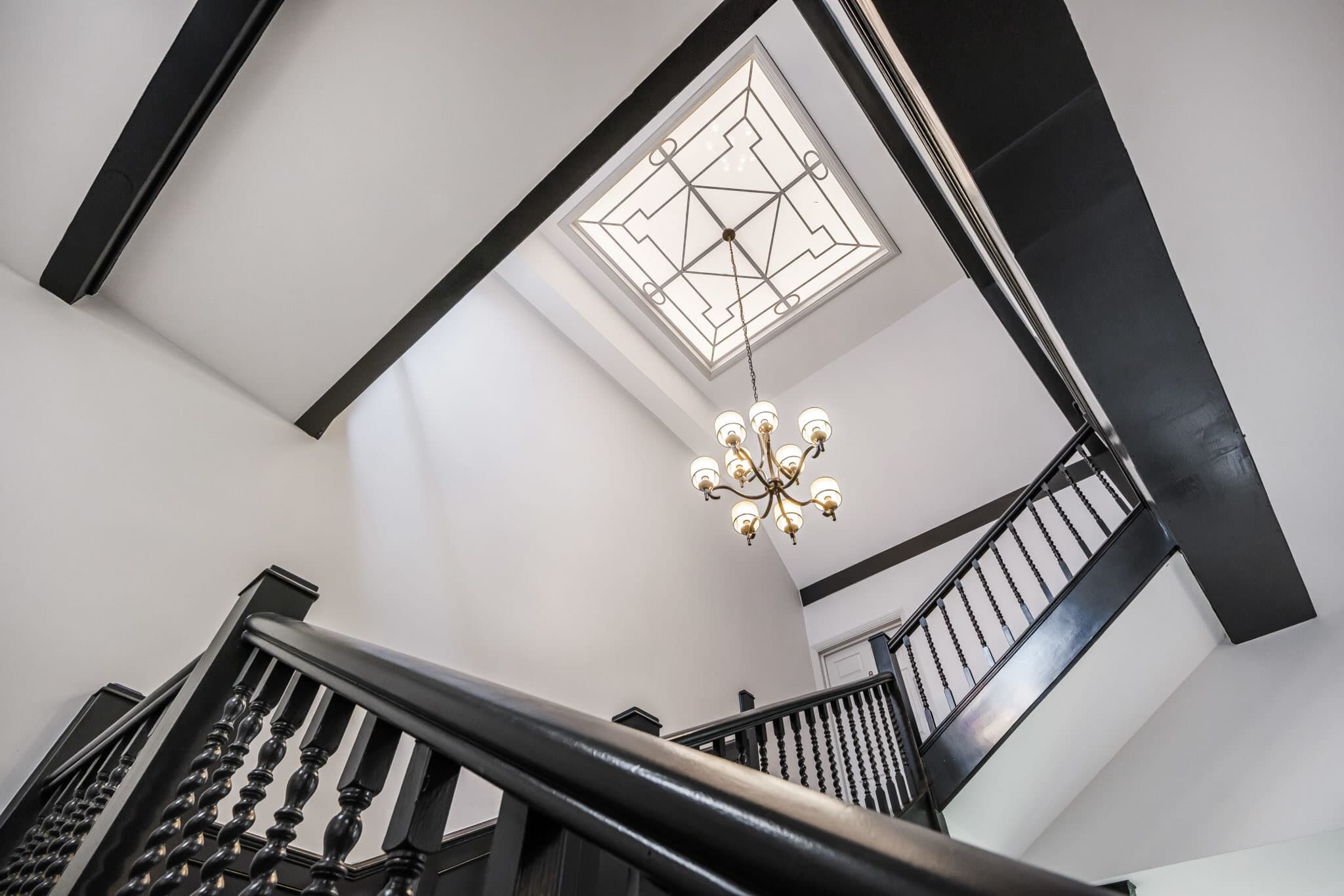 Galleried staircase beneath a decorative skylight, restored by House Plus Builders